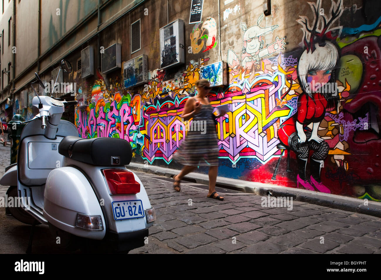 Mädchen zu Fuß hinunter Hosier Lane, neben Graffiti und Moped, Melbourne Stockfoto
