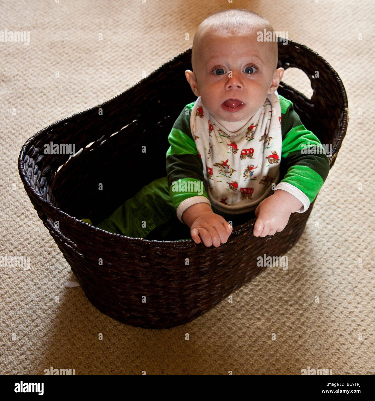 Baby Boy (acht Monate alt) spielt in einem Korb Stockfoto