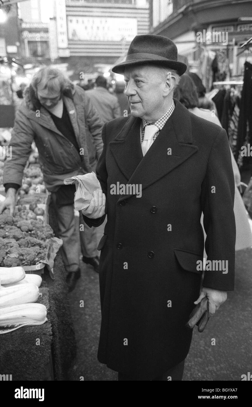 Sir Alec Guinness, der Schauspieler, den er im Old Country, im Queens Theatre, Shaftesbury Avenue, gespielt hat. London, England, ca. 1977. Soho-Markt, der Obst kauft, bevor er ins Theater geht 1970er UK HOMER SYKES Stockfoto