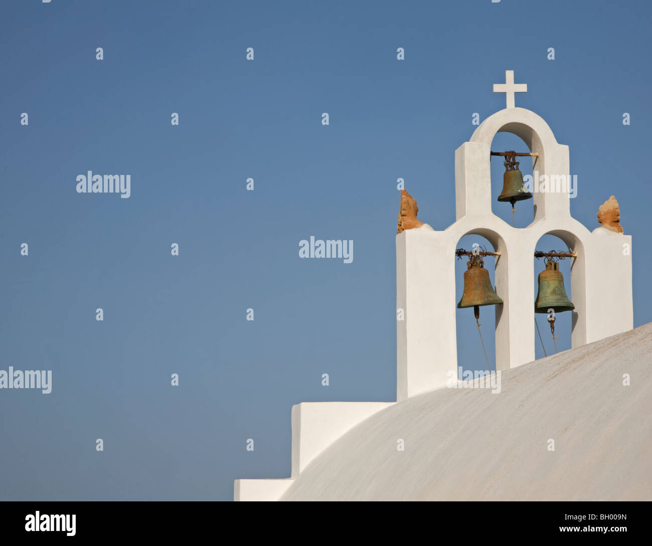 Weißer Kirchenglockenturm mit Kreuz und klarem blauem Himmel auf der Insel Santorin in Griechenland Stockfoto
