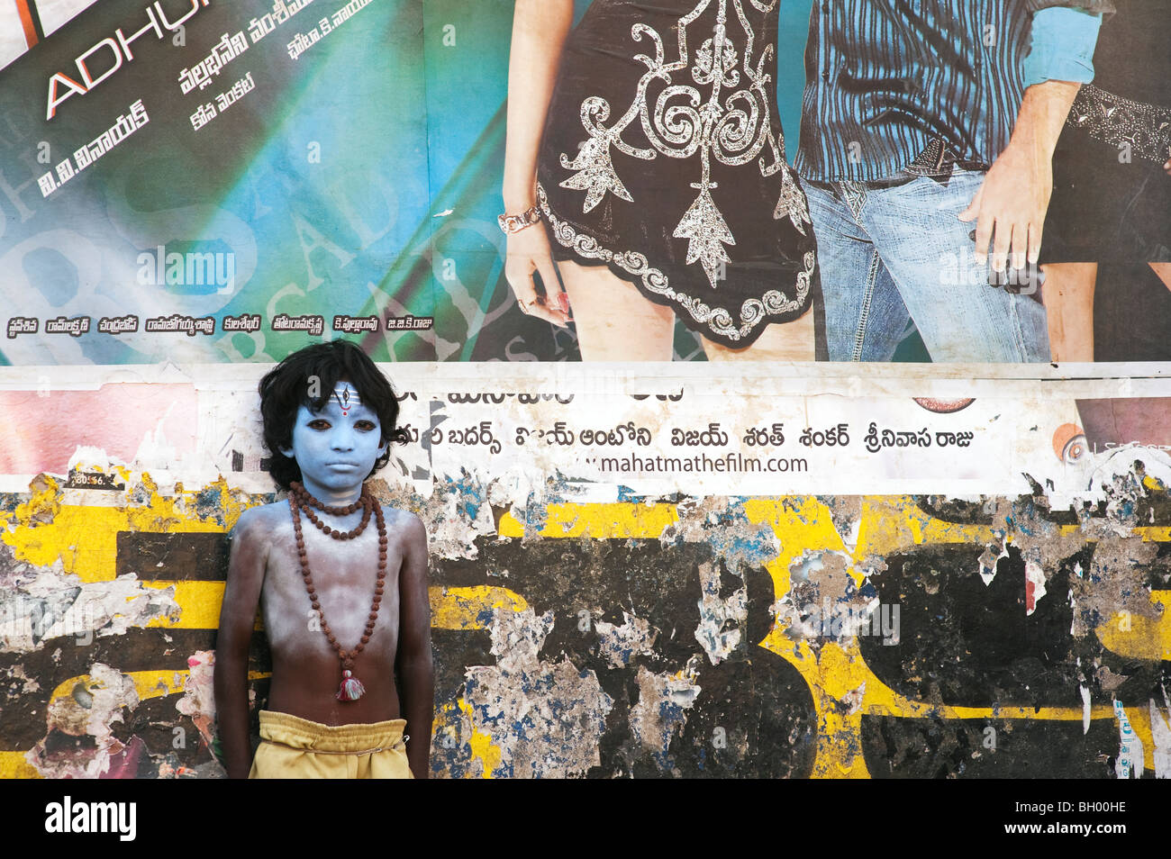 Indischer Junge, Gesicht gemalt als Hindu Gott Shiva vor einem Bollywood Film Poster. Andhra Pradesh, Indien Stockfoto