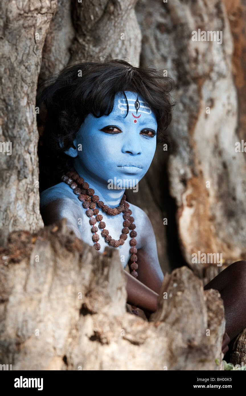 Indischer Junge, Gesicht gemalt als Hindu Gott Shiva in einem alten Baumstumpf sitzen. Andhra Pradesh, Indien Stockfoto Indischer Junge, Gesicht gemalt als Hindu Gott Shiva in einem alten Baumstumpf sitzen. Andhra Pradesh, Indien Stockfoto