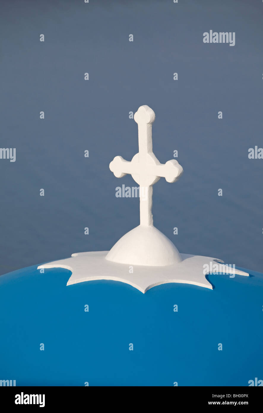 Sonnenbeschienene weiße Kreuze auf der blau gewölbten St. Gerasimos Christian Church in Firostefani, vor dem blauen Hintergrund des Mittelmeers Stockfoto