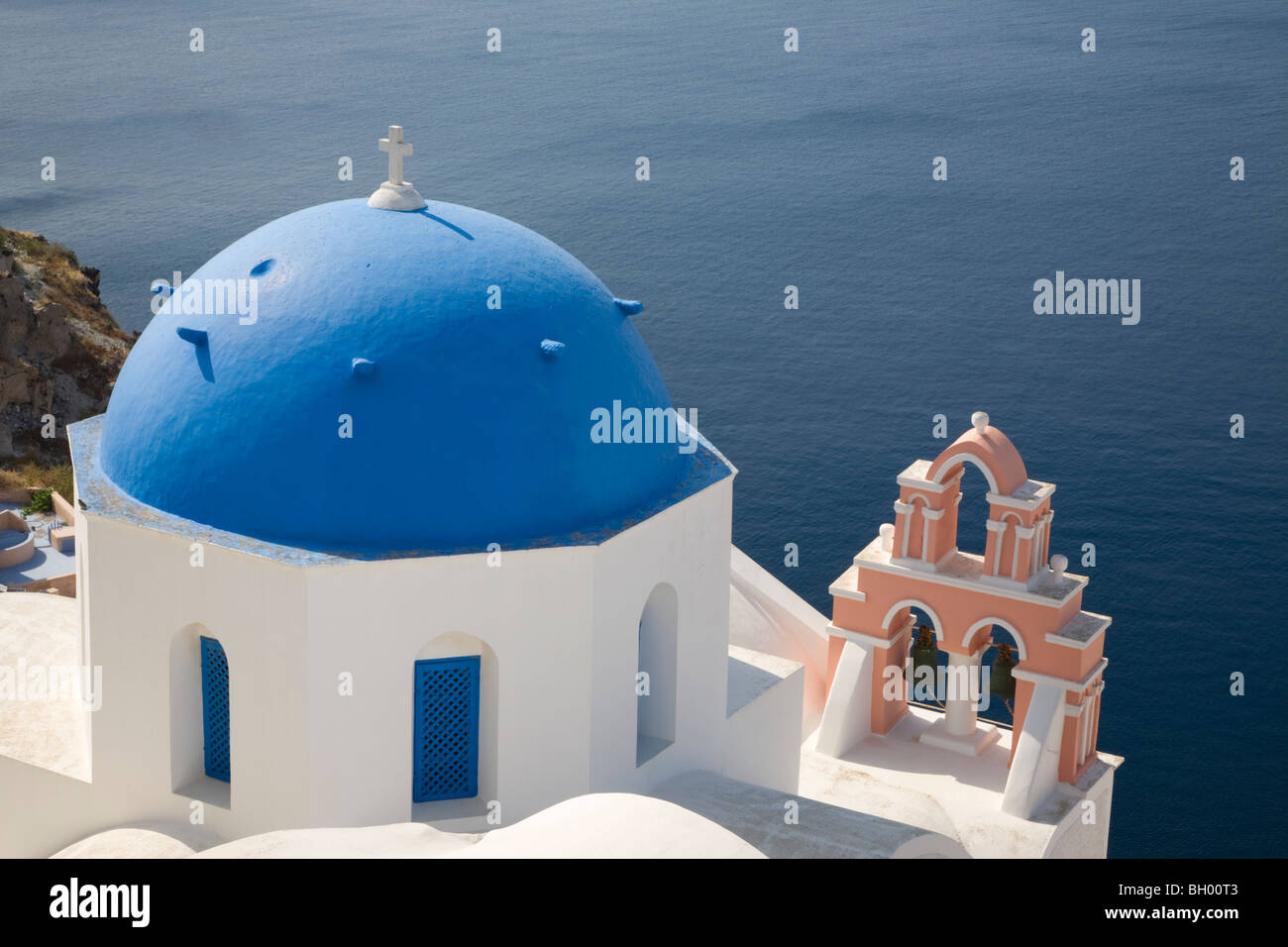 Blaue Kuppelkirche und Glockenturm in einem Dorf mit Blick auf Santorinis Lagune, Oia, Griechenland Stockfoto