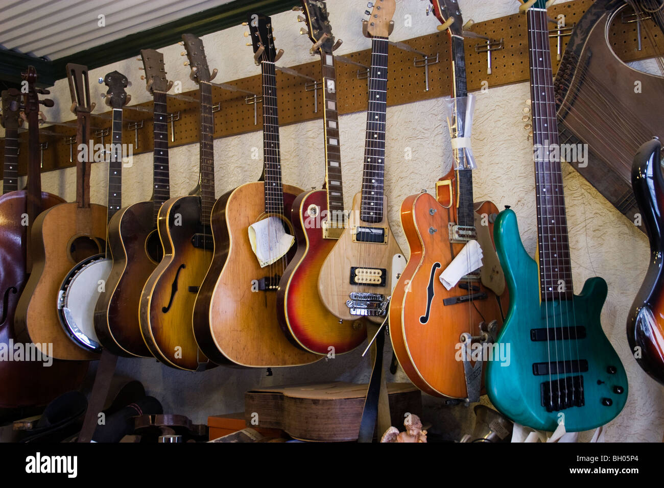 Eine Ansammlung von Streichinstrumenten, die Reparatur in einem Gitarrenbauer-Shop warten. Stockfoto