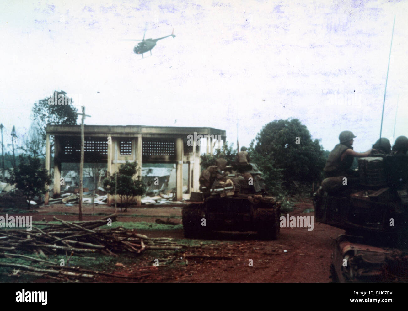11. Armored Cavalry 48 Panzer, Pass, beschädigte Gebäude am Stadtrand von Snoul. OH-6A Cayuse (Schmerlen) leichte Hubschrauber fliegen Stockfoto