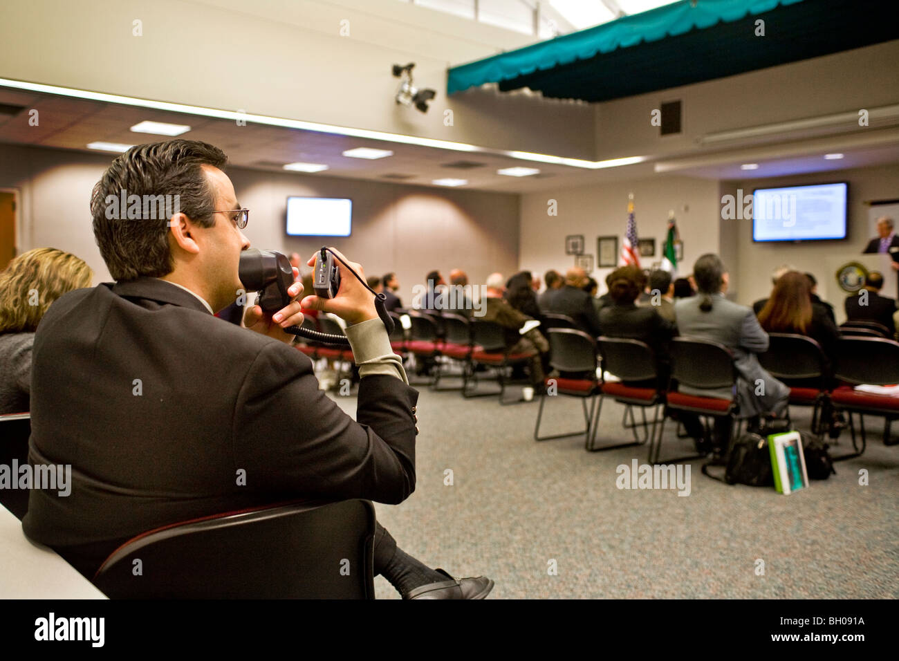 Mit einem Mikrofon und schnurlosen Sender, hilft ein Hispanic Simultandolmetscher Spanisch-sprachigen Konferenzteilnehmern. Stockfoto