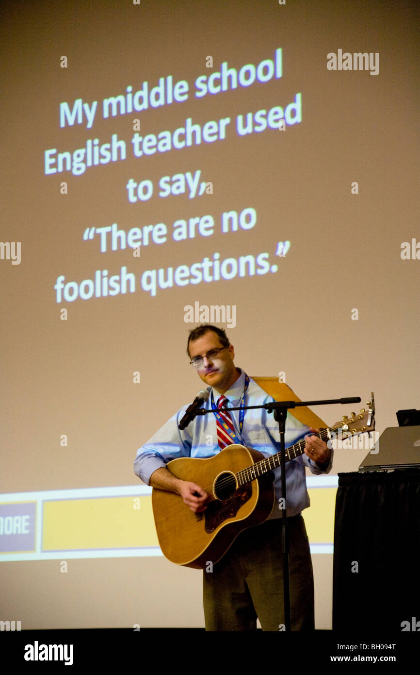 Vor seiner Rede für Erzieher ruft eine Highschool Englischlehrer sein Publikum in eine rezeptive Stimmung ein Lied von ihm. Stockfoto