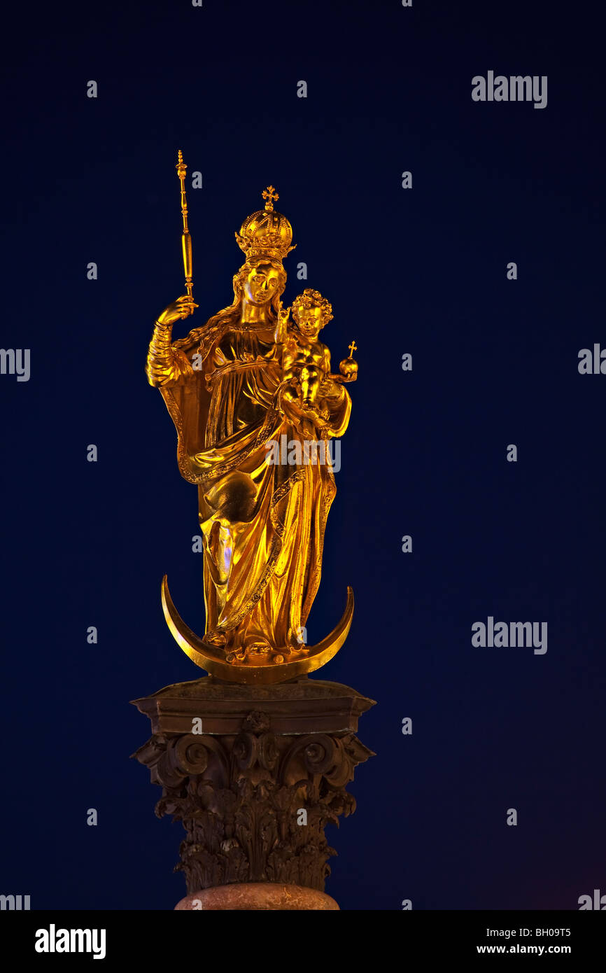 Goldene Statue der Jungfrau Maria auf der Mariensäule in der Marienplatz in der Abenddämmerung in der Stadt München (München), Bayern, Deutschland Stockfoto