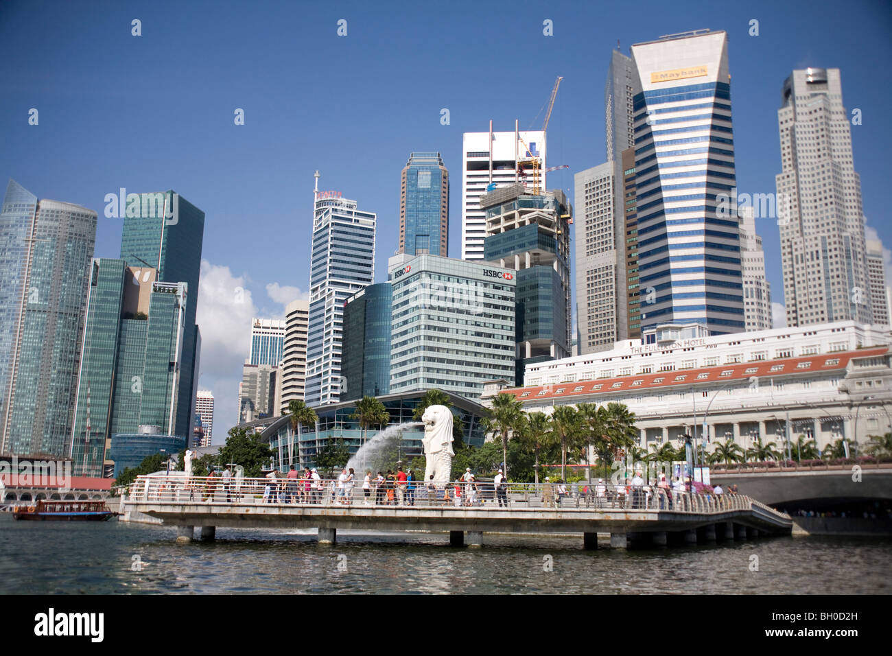 Singapur. Merlion-Brunnen am Wasser mit Gebäude der Stadt im Hintergrund. Stockfoto