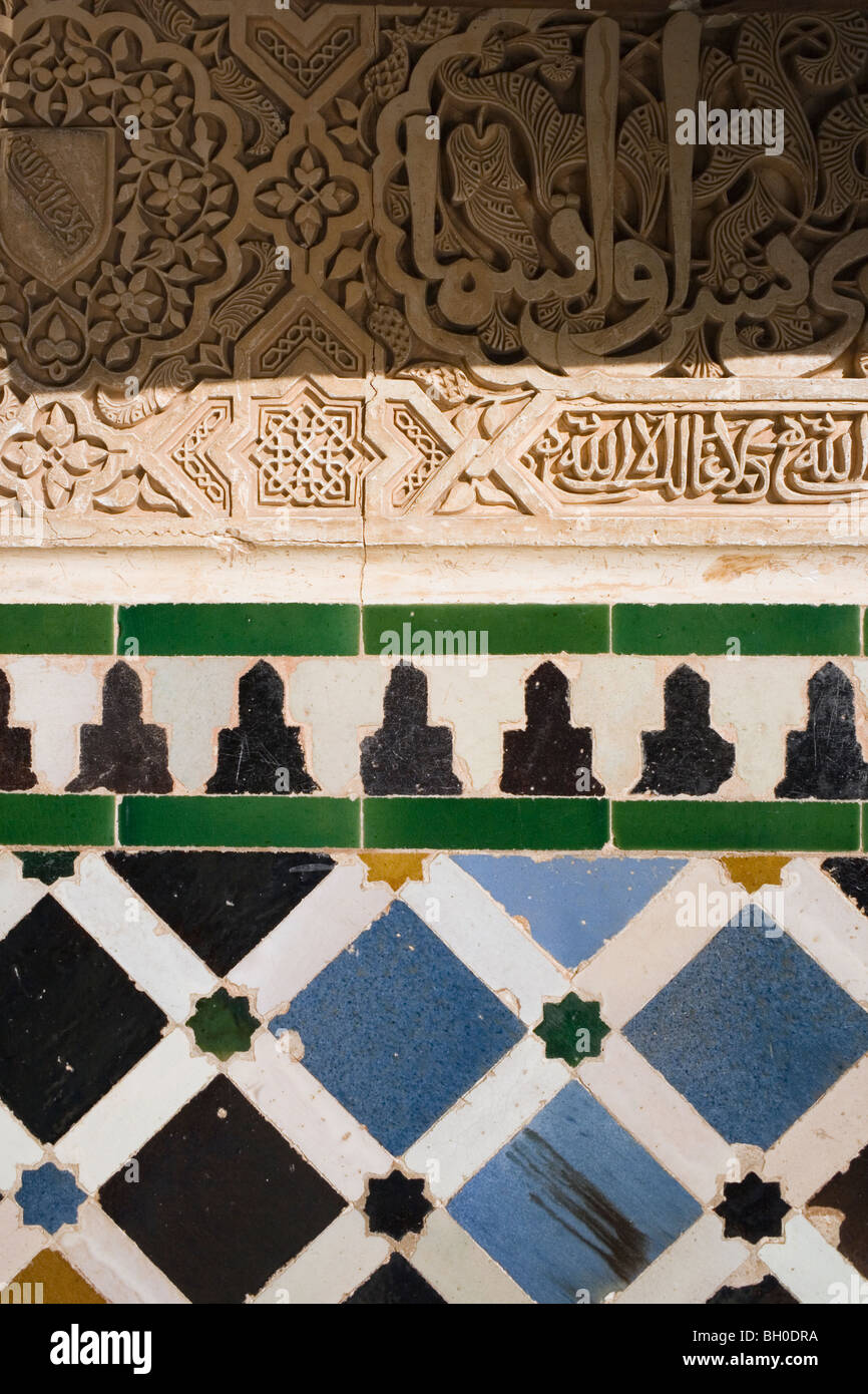 Palast von Alhambra, Granada, Andalusien, Spanien. Detail der kunstvoll geschnitzten Wand und Fliesen. Stockfoto