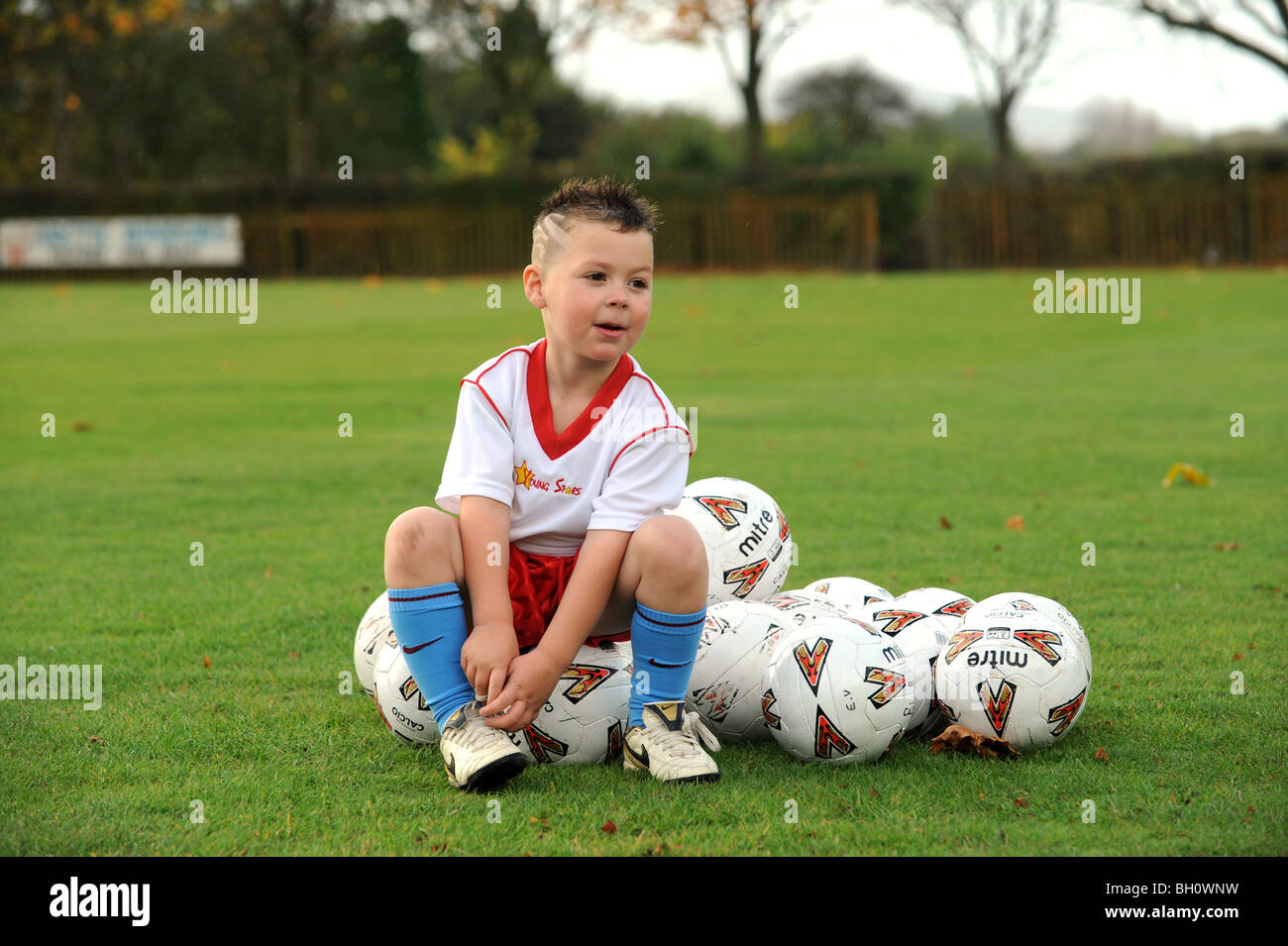 Kleiner Junge fesselt seine Schnürsenkel bereit für Fußball coaching Stockfoto
