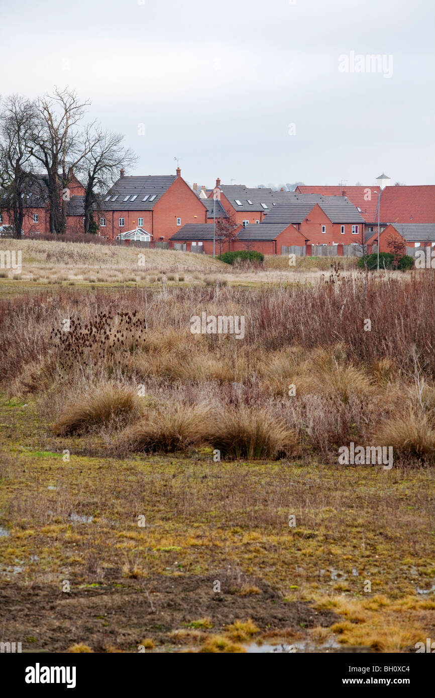 Eine neue Wohnsiedlung in Northampton, UK, mit Land im Vordergrund, die noch nicht bebaut. Stockfoto
