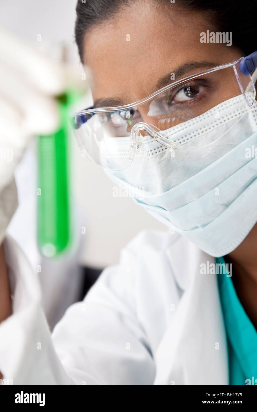 Weibliche asiatische medizinische oder wissenschaftliche Forscher oder Arzt ein Reagenzglas eine grüne Lösung in einem Labor zu betrachten. Stockfoto