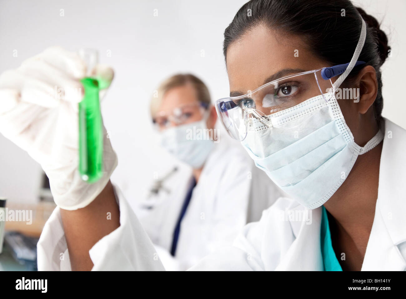 Weibliche asiatische medizinische oder wissenschaftliche Forscher oder Arzt Blick auf ein Reagenzglas eine grüne Lösung in einem Labor Stockfoto
