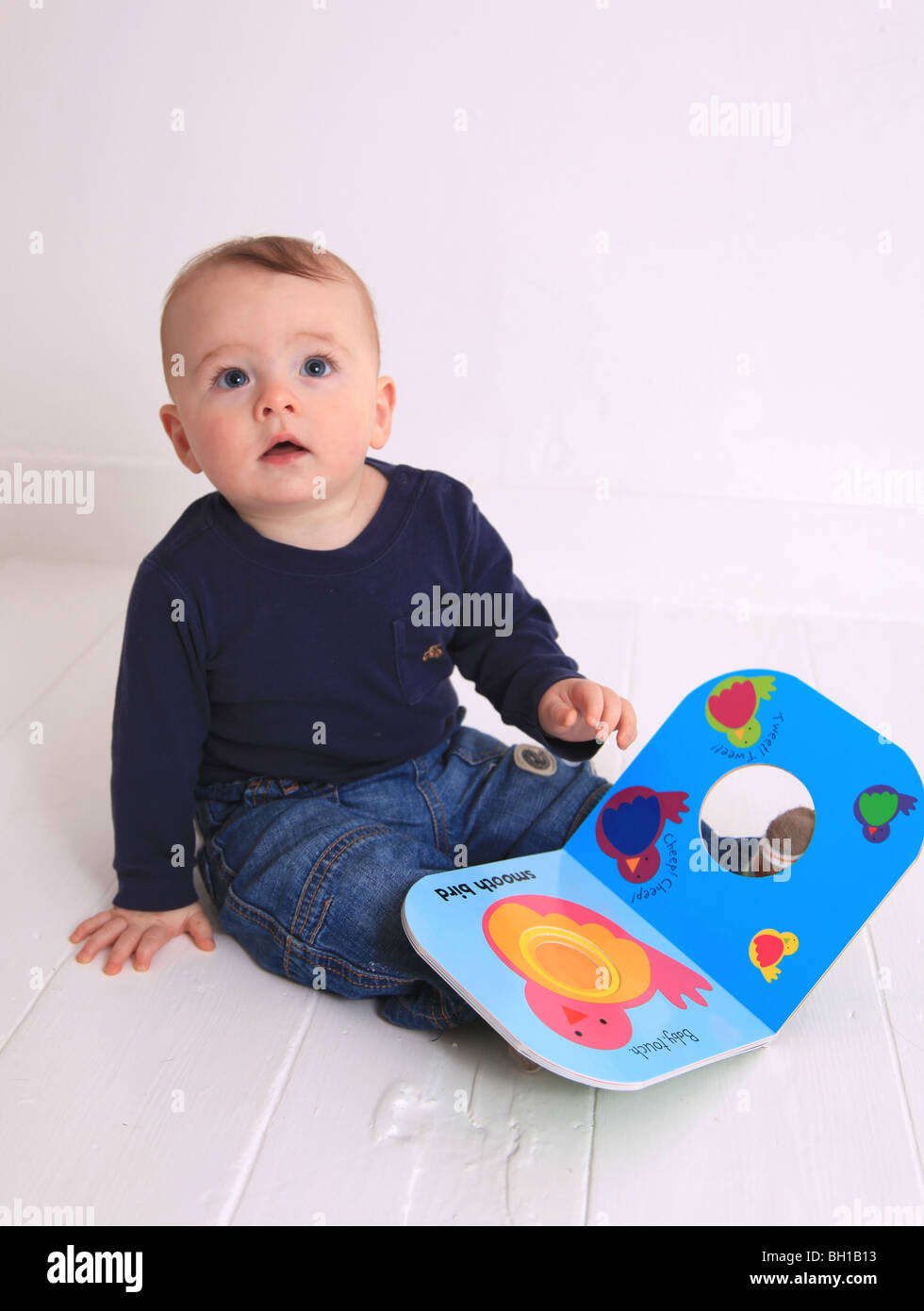 6 Monate altes Baby Junge sitzt mit Pappband. Stockfoto