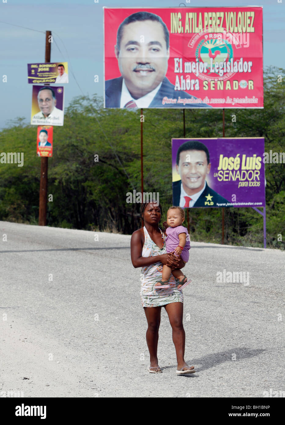 Eine Frau und Kind Fuß auf der Straße vorbei an politischen Plakatwerbung, Südwest Dominikanische Republik Stockfoto