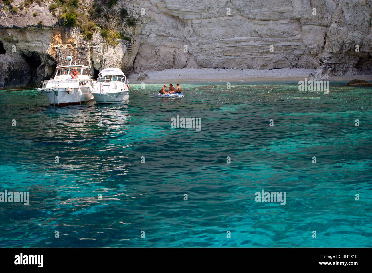 Boote ankern vor Höhlen an der Westküste, Paxos, Ionische Inseln, Griechenland Stockfoto