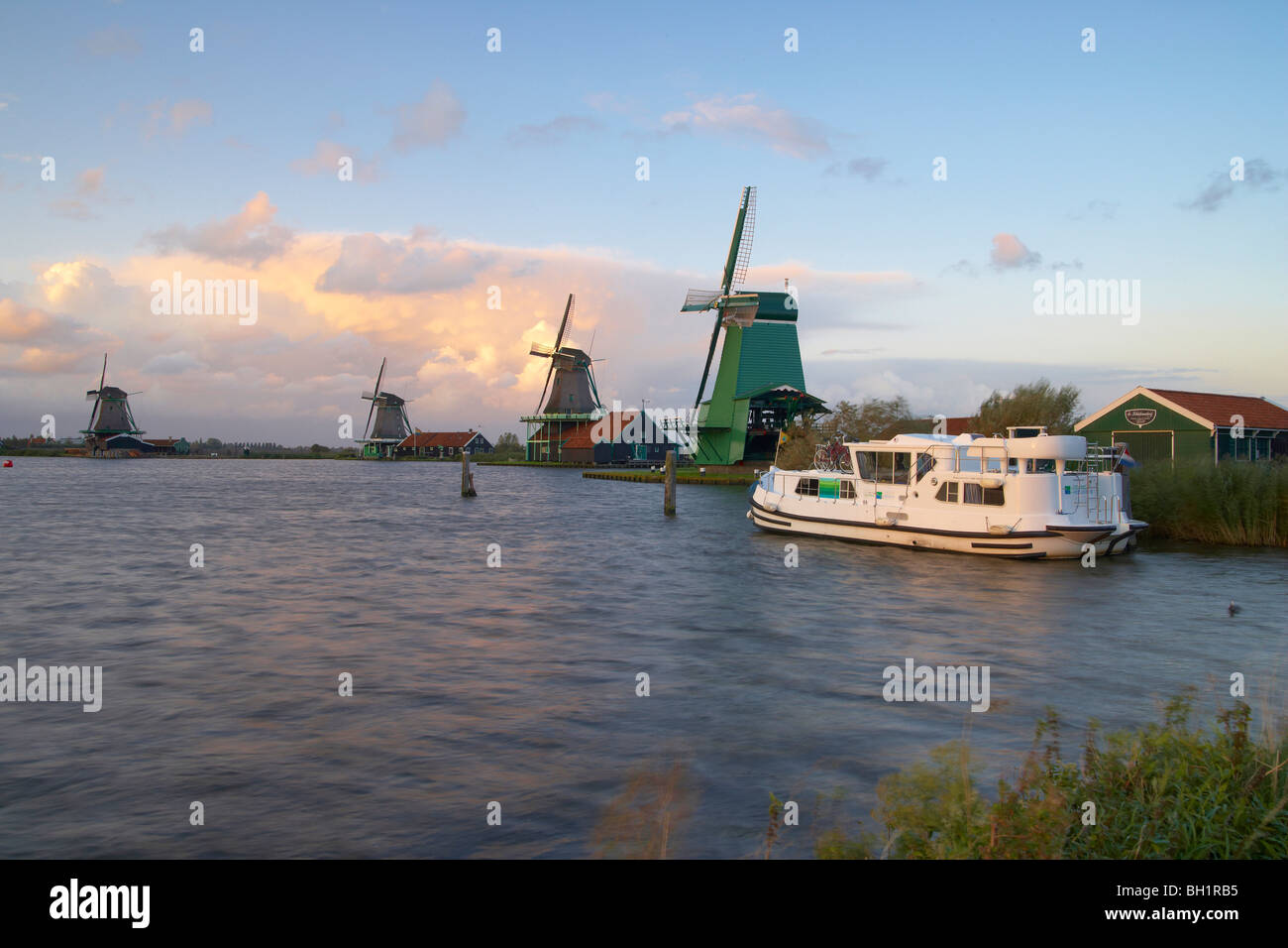 Ein Boot und Windmühlen im Abend, Open-Air-Museum Zaanseschans am Fluss Zaan, Niederlande, Europa Stockfoto
