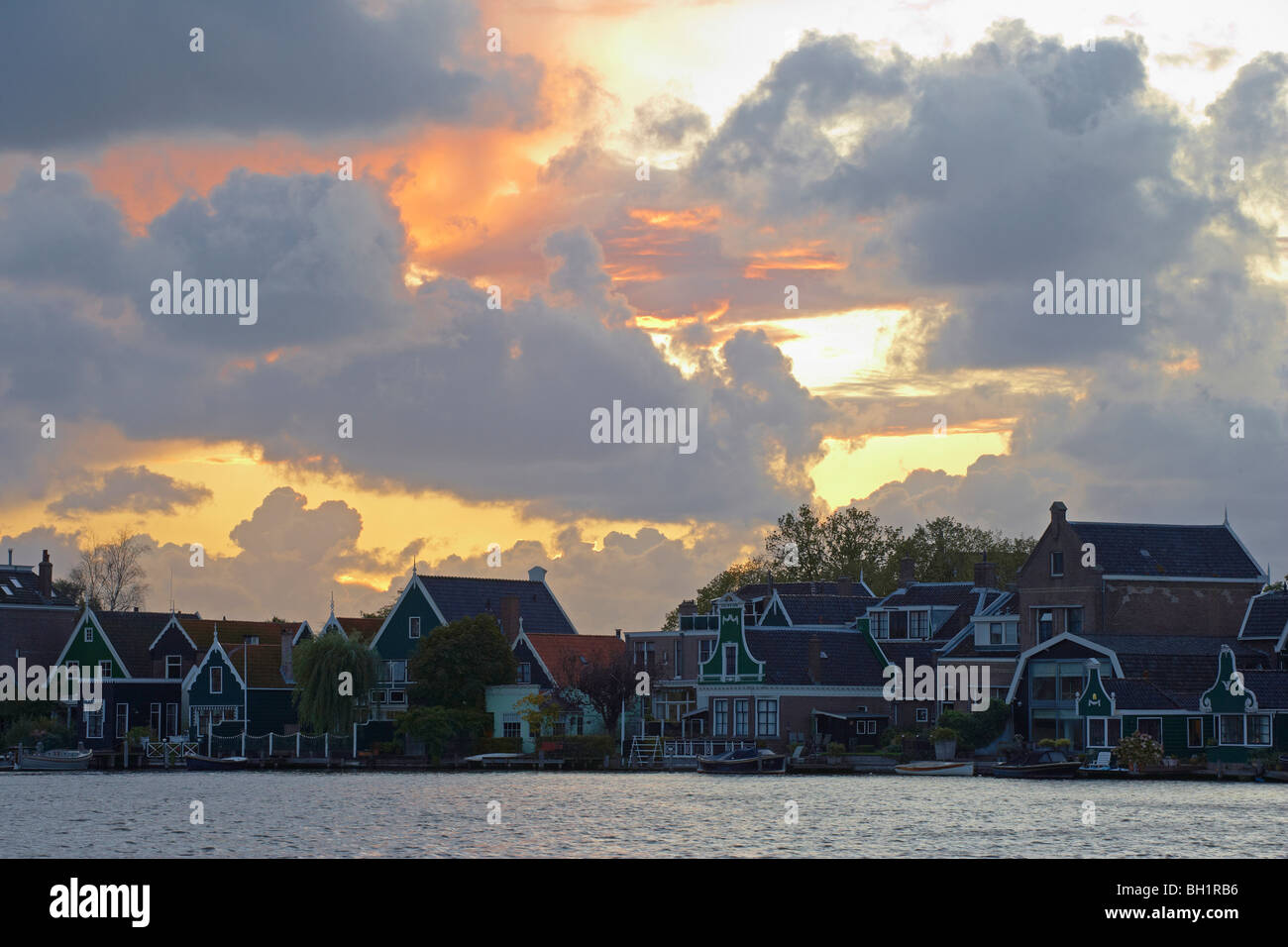 Historische Häuser am Fluss Zaan unter bewölktem Himmel bei Sonnenuntergang, Zaandijk, Niederlande, Europa Stockfoto