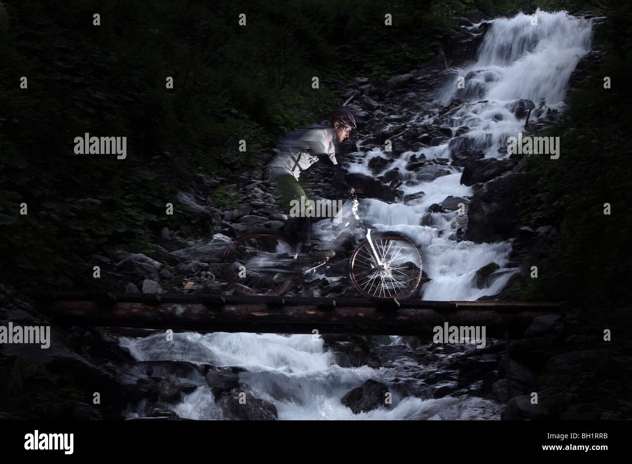 Mountainbiker fahren über eine Brücke vor einem Wasserfall, Ischgl, Tirol, Österreich Stockfoto