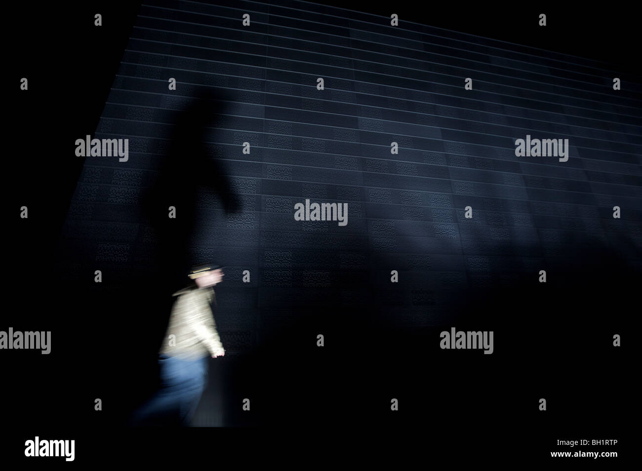 Person zu Fuß vorbei an einer Wand in der Nacht, Oslo, Norwegen Stockfoto
