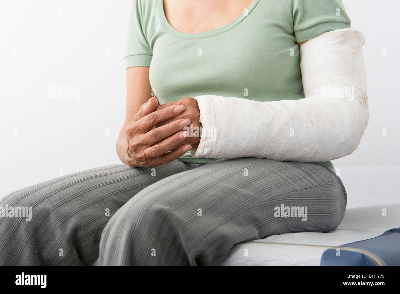 Ältere Frau sitzt mit Gips auf gebrochenen Arm, Mittelteil Stockfoto