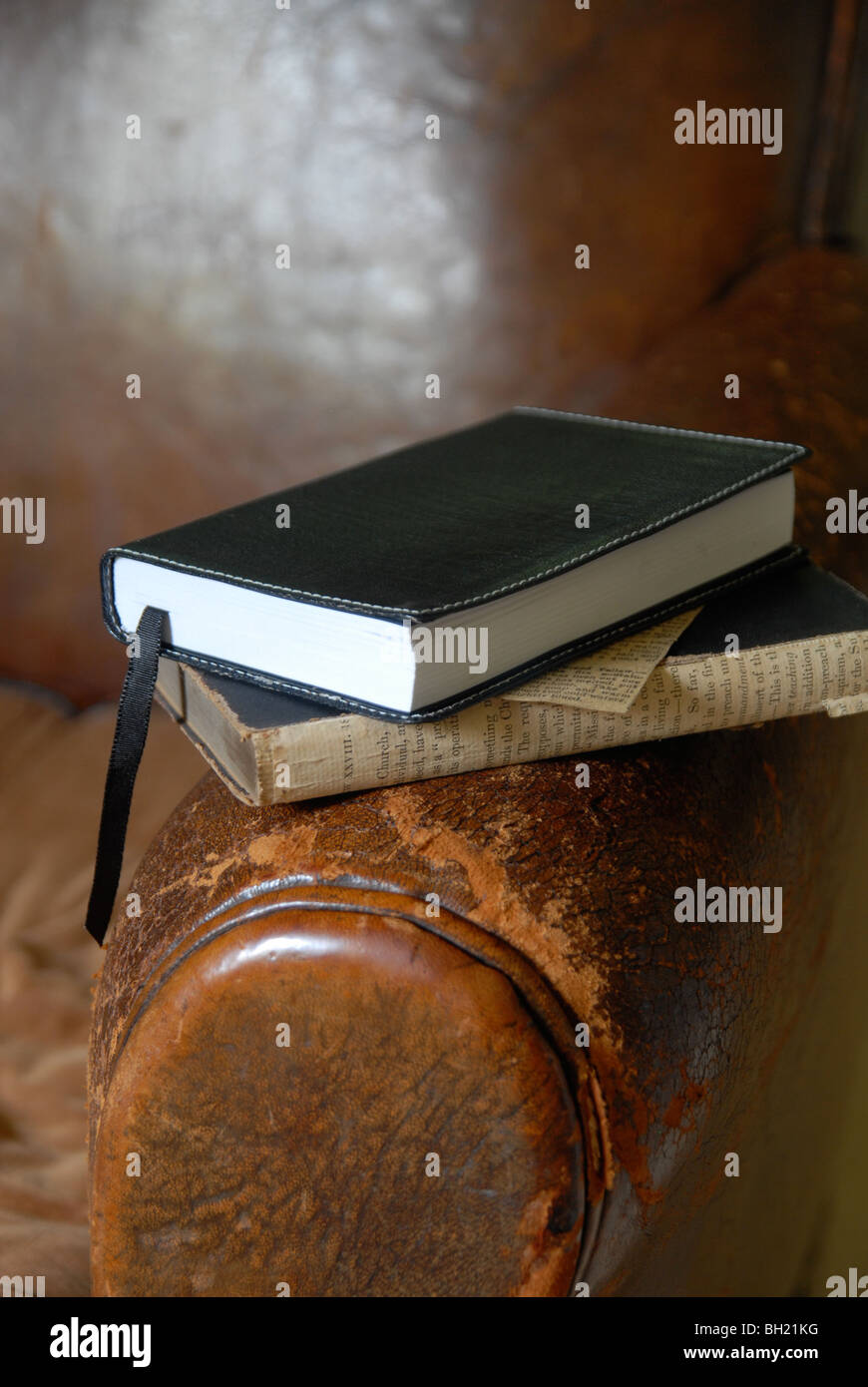 Eine einfache Stilleben von zwei Büchern auf dem Arm des einen alten Ledersessel. Stockfoto
