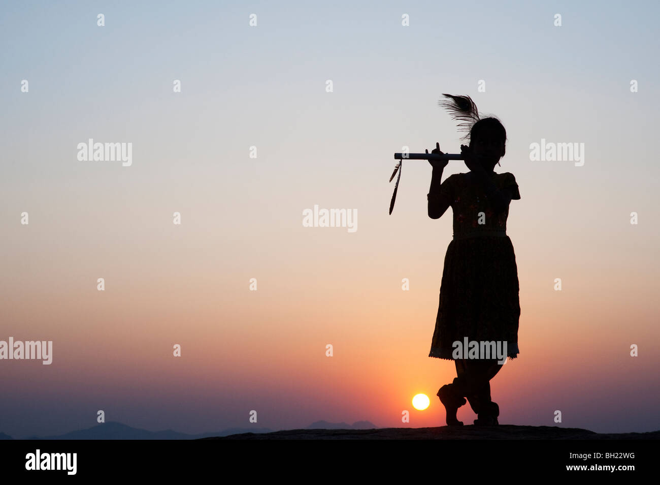 Silhouette eines indischen Mädchens vorgibt, Lord Krishna bei Sonnenuntergang. Andhra Pradesh, Indien Stockfoto