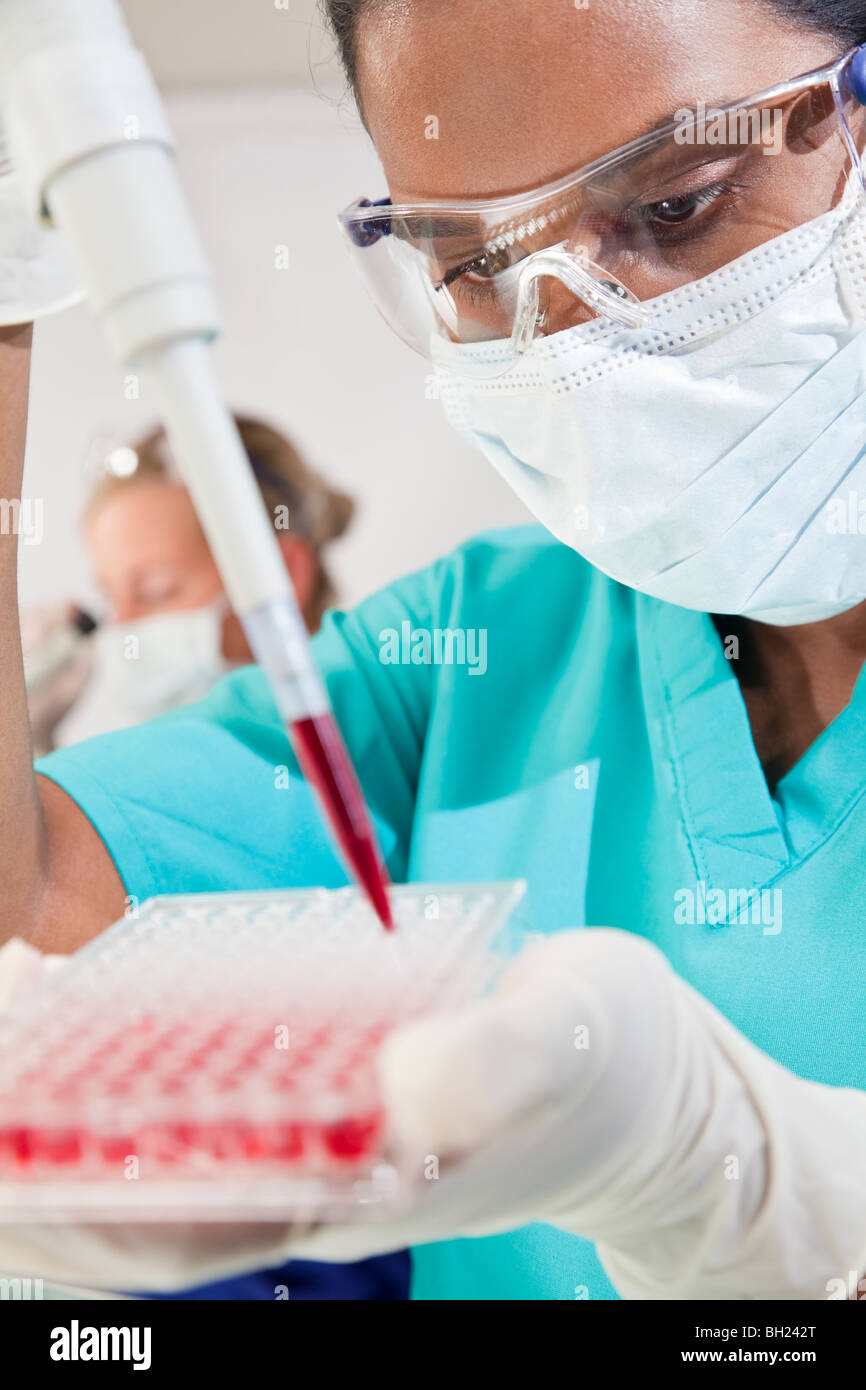 Weibliche asiatische medizinische oder wissenschaftliche Forscher oder Arzt über eine Pipette und Probe Fach Blutprobe im Labor testen Stockfoto