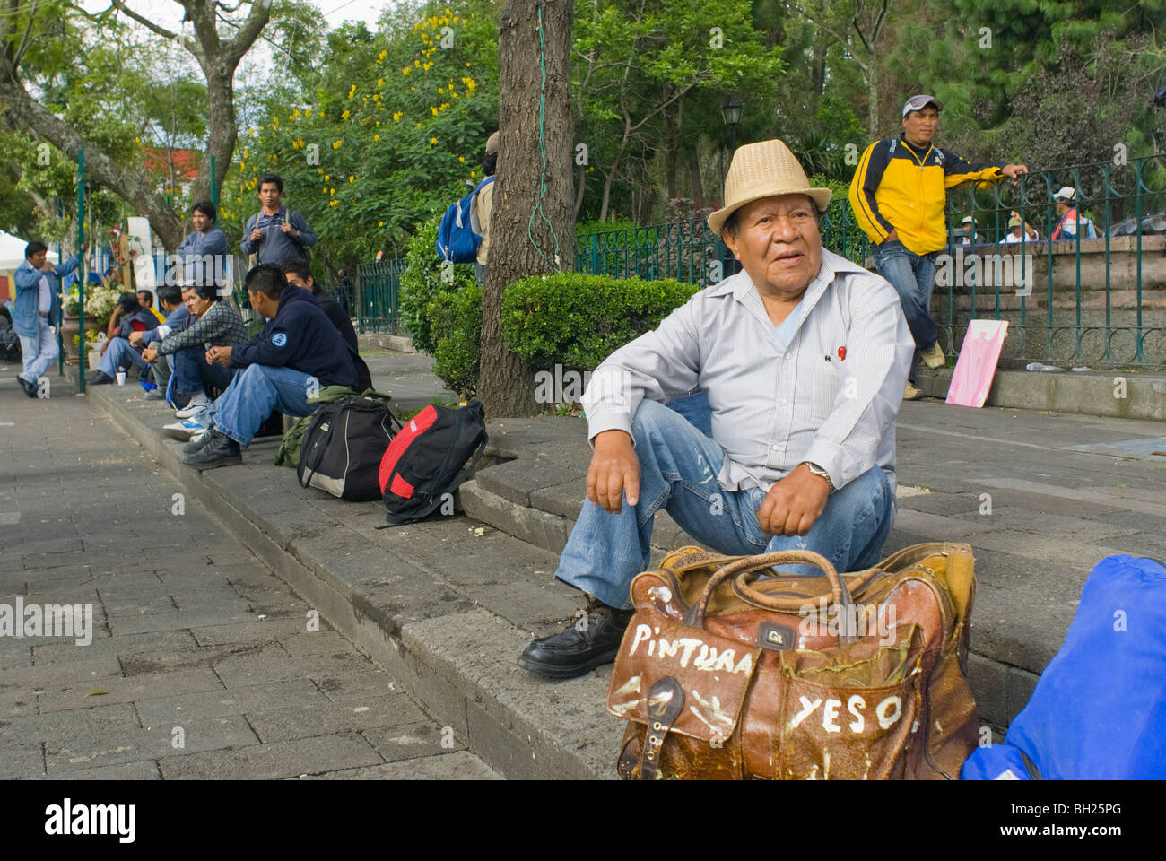 Guillermo Herrera Guzmán, 79, wartet Arbeit auf den Stufen des einen öffentlichen Platz mit seiner Malerei und Verputzen Werkzeuge. Stockfoto