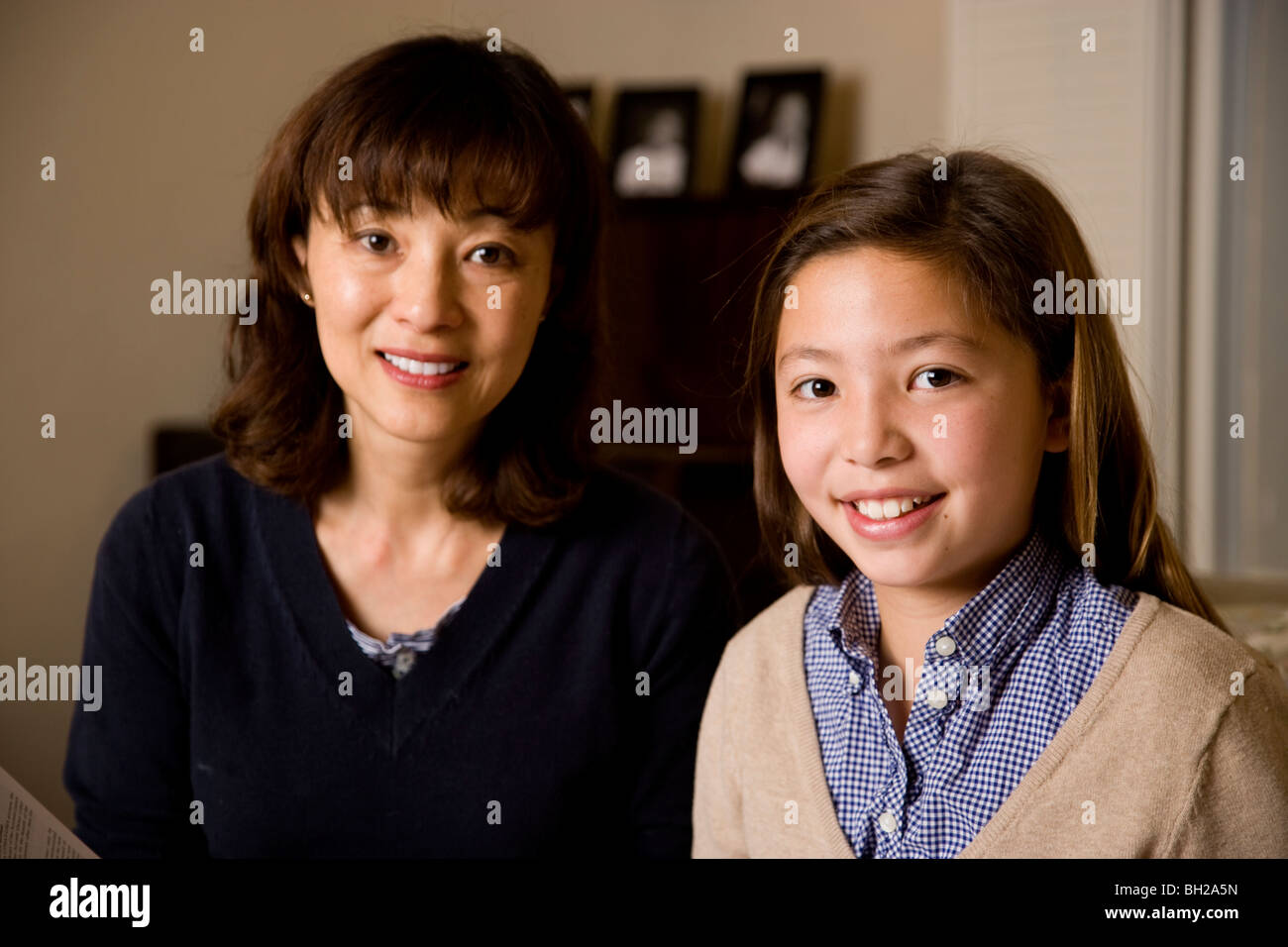 Koreanische Mutter und Koreanisch/weiß Tochter zu Hause in ihrem Wohnzimmer. Tochter ist Schlüssel im Porträt, Mutter hinter ihr. Stockfoto