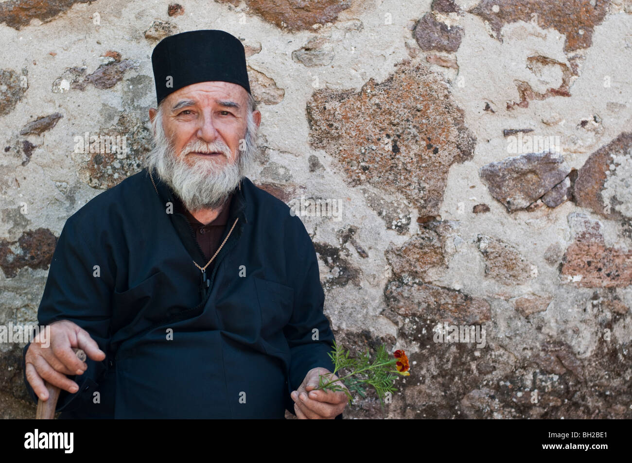 Traurig ältere griechisch-orthodoxen Priester in Roben und Bart mit Rohrstock Stockfoto