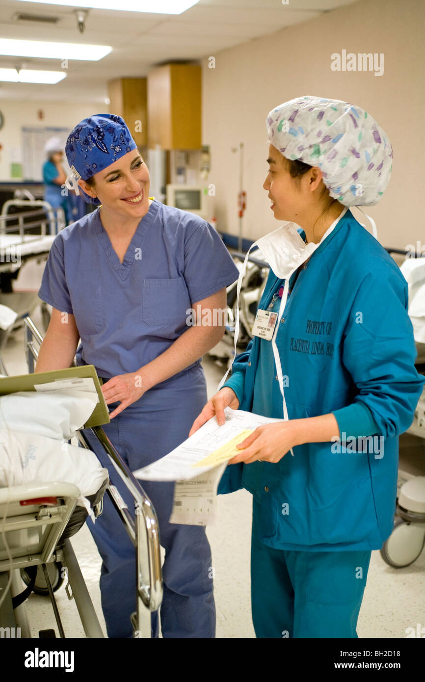 Gekleidet in "Scrubs", prüft ein Chirurg Frau mit ihrer umlaufenden Krankenschwester über medizinische Berechtigungen vor einer Operation. Stockfoto
