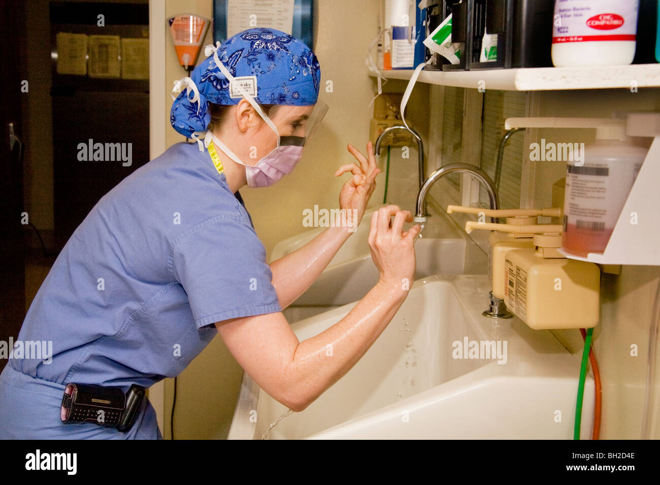 In "Scrubs" gekleidet und tragen einen Mundschutz, wäscht Chirurges Frau ihre Hände gründlich vor dem Ausführen eines Vorgangs. Stockfoto