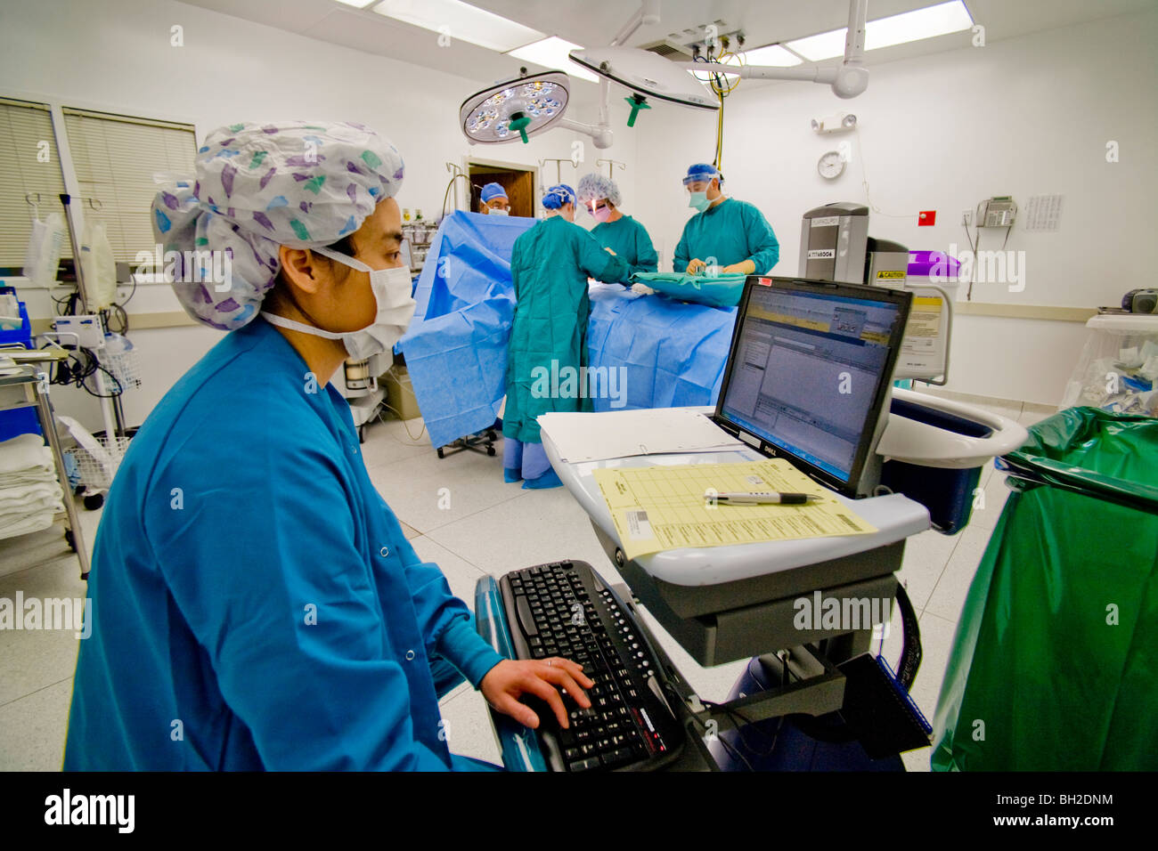 Auf einem Computer während einer Operation in einem Krankenhaus in Südkalifornien überwacht eine asiatischen zirkulierende Krankenschwester Zustand des Patienten. Stockfoto