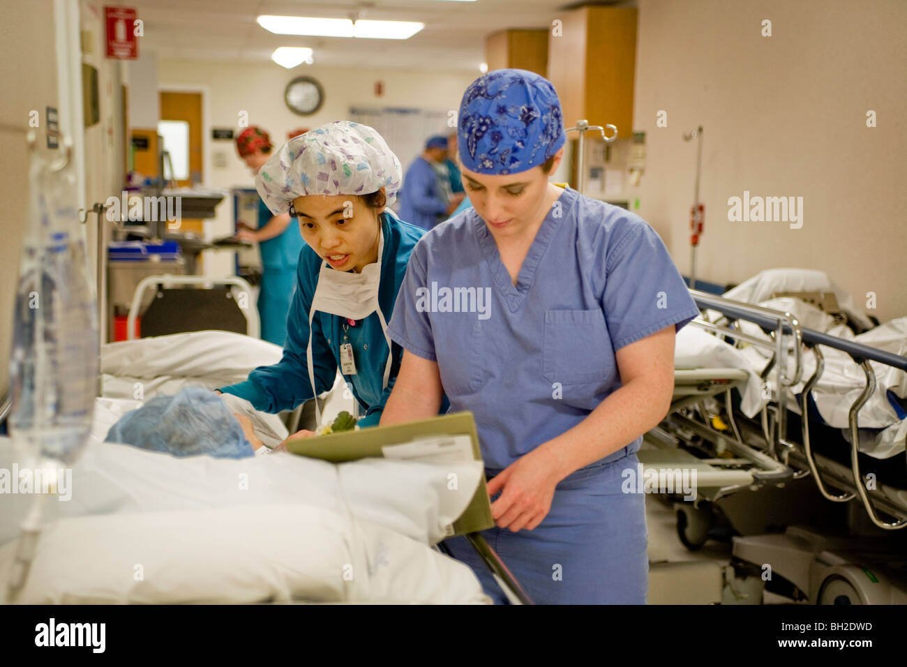 Gekleidet in "Scrubs", Frau Chirurg und ihr zirkulierenden Krankenschwester medizinische Berechtigungen zu überprüfen und beruhigen ihre Patienten (links). Stockfoto