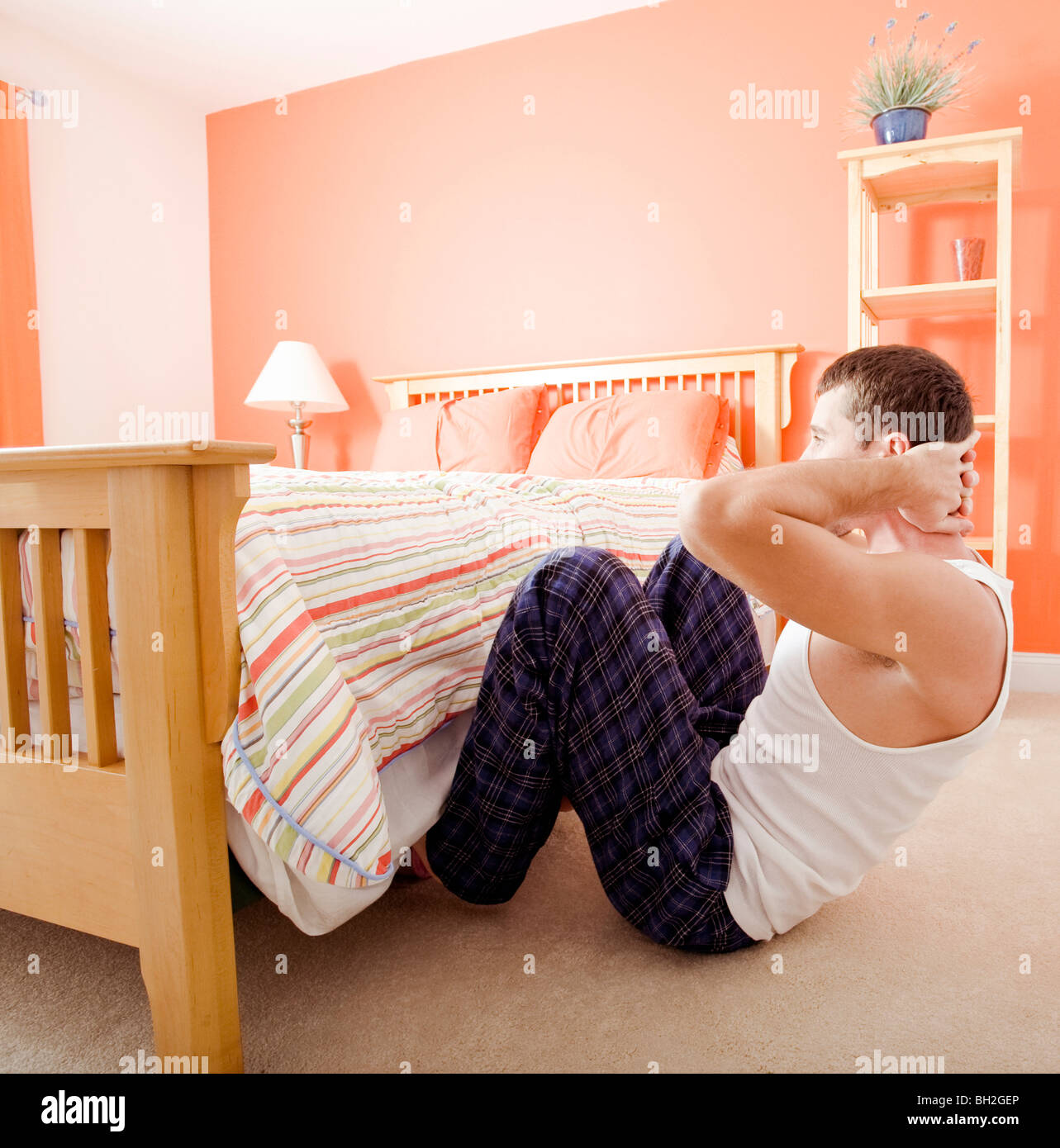 Mann Sit in seinem Schlafzimmer, mit den Füßen, die versteckt unter den Bettrahmen. Quadratisches Format. Stockfoto
