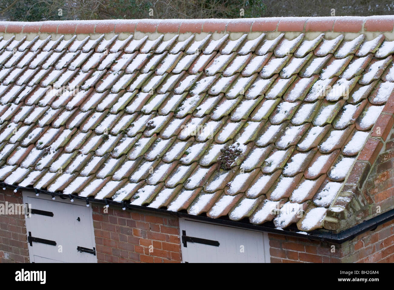 Schnee und Hagel Steinen auf Flachdachziegel Dach von einem Nebengebäude. Stockfoto
