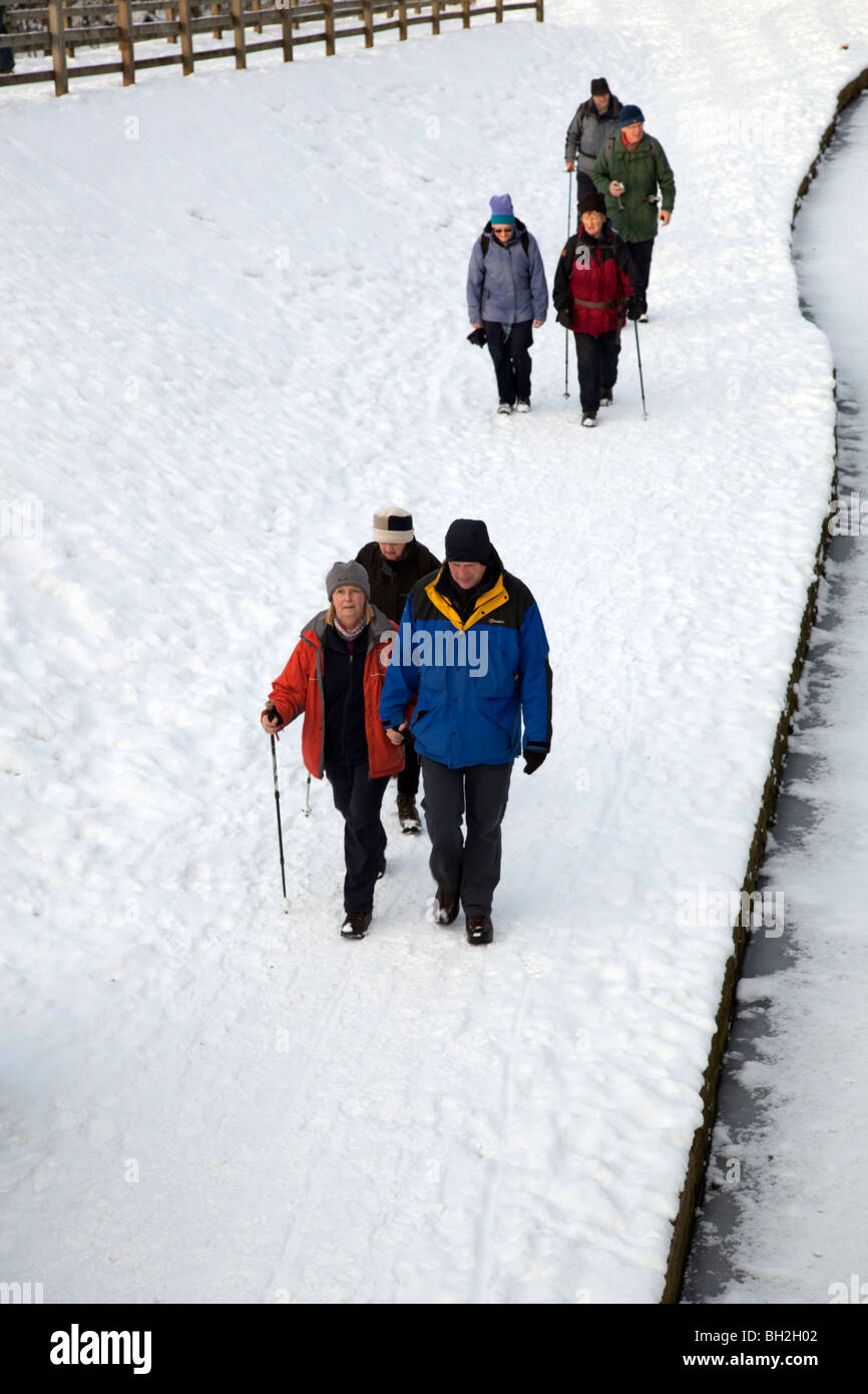 Gruppe von Wanderern, genießen den Schnee entlang der Chesterfield Kanal Leinpfad Derbyshire England Stockfoto