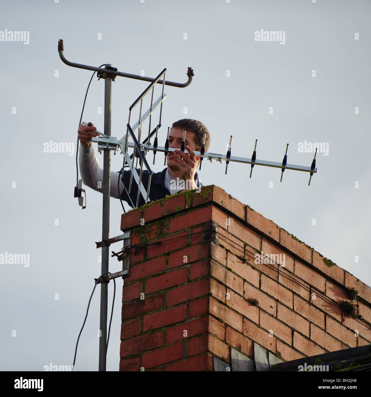 Ein TV-Ingenieur installieren neue digitale tv kompatibel Antenne an einem Schornstein eines Hauses Stockfoto