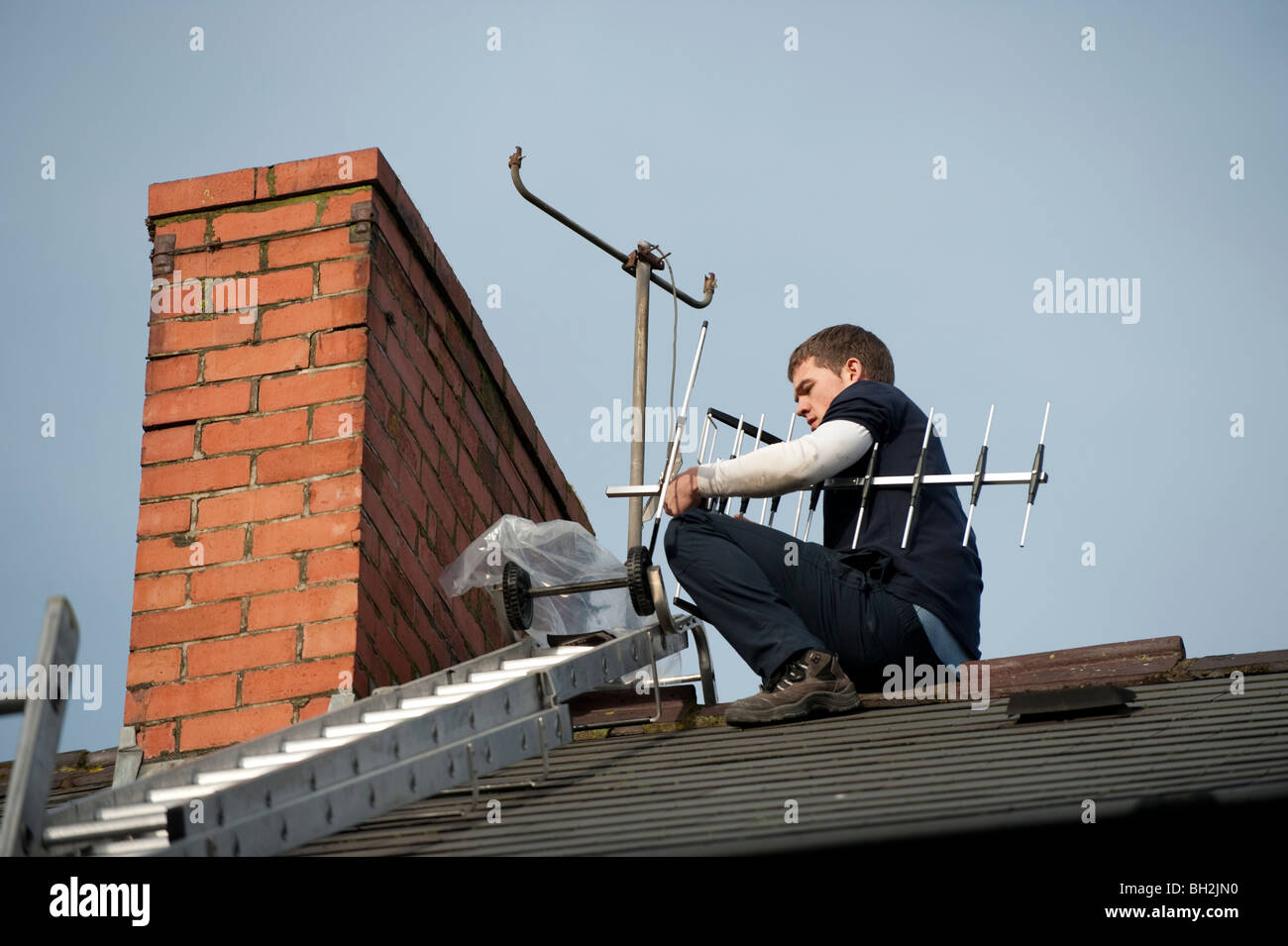 Eine junge TV-Ingenieur installieren neue digitale tv kompatibel Antenne an einem Schornstein eines Hauses Stockfoto