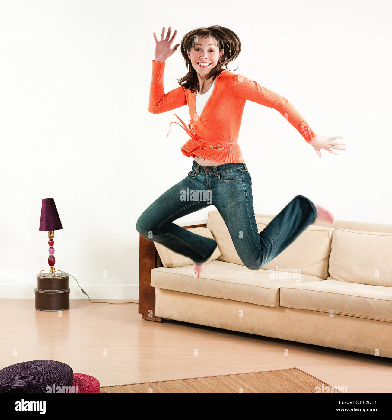 glückliche Frau in einem Wohnzimmer springen Stockfoto