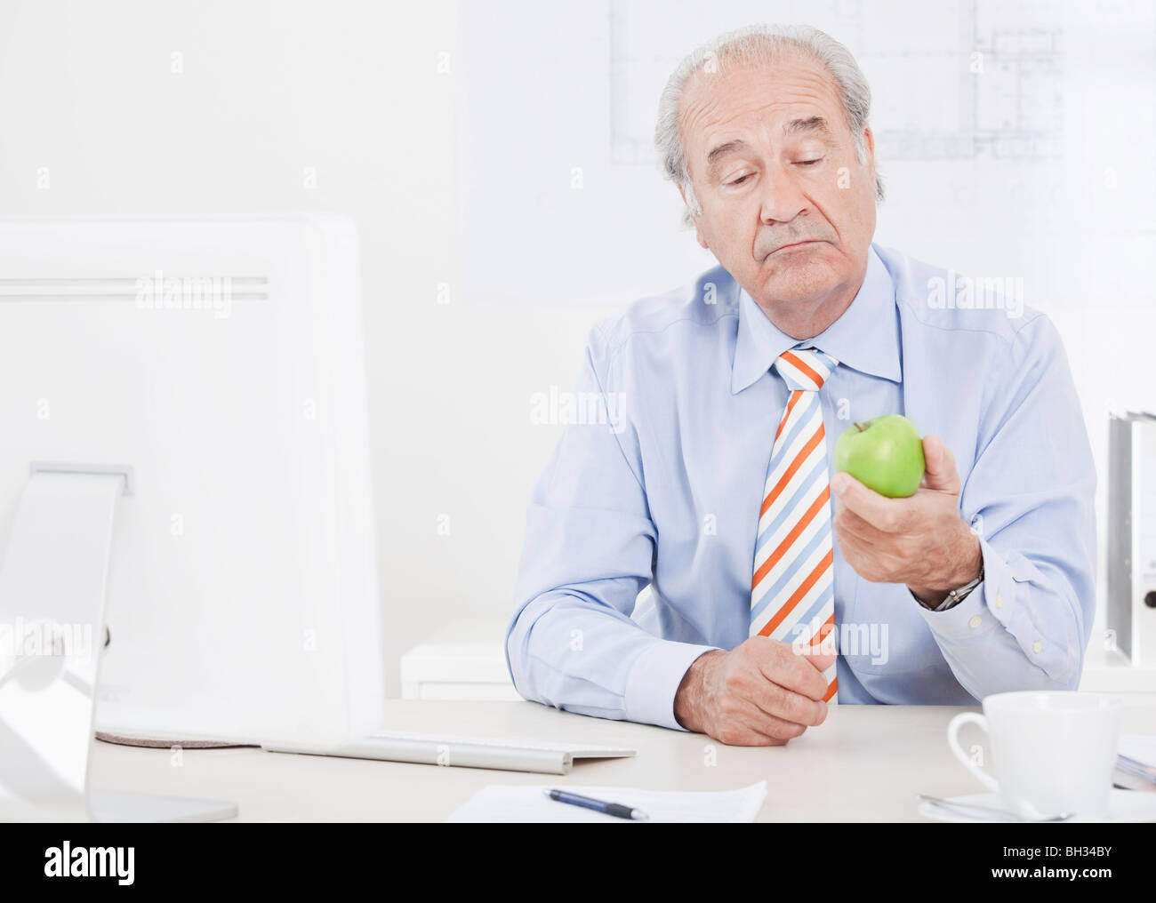 Mann sucht zweifelnd an einen Apfel Stockfoto