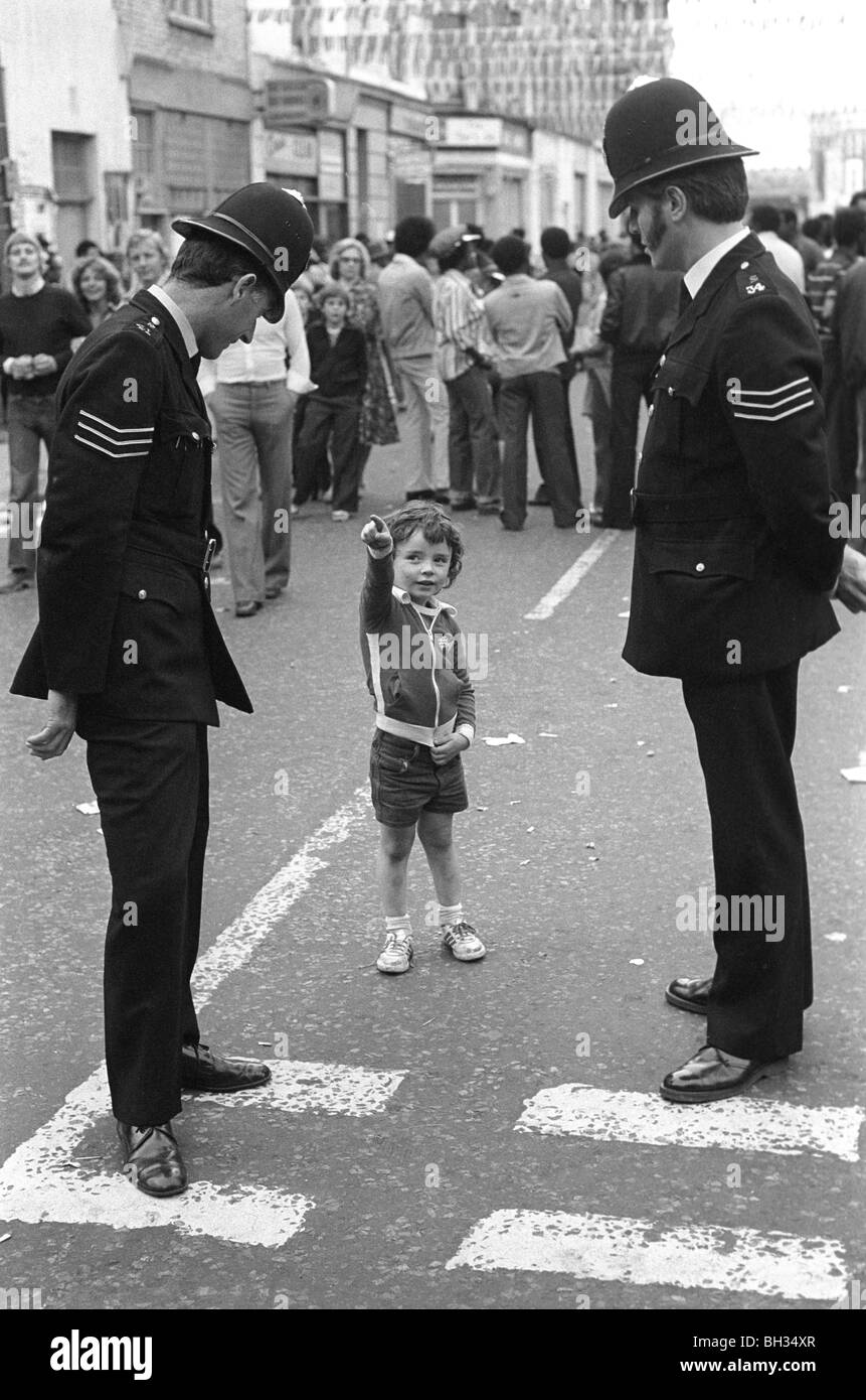 Polizei aus den 1970er Jahren mit dem kleinen Jungen Notting Hill West London. Gemeindepolizisten sind auf dem Schlag. 1970 UK HOMER SYKES Stockfoto