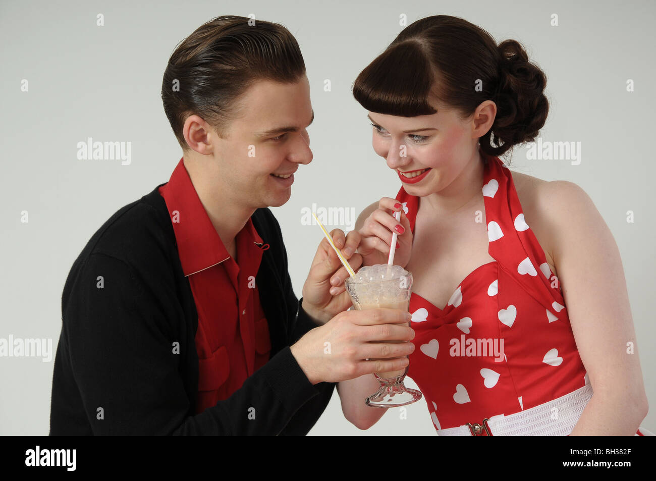 Paar in der 1950er Jahren Kleidung teilen einen Milchshake. Stockfoto