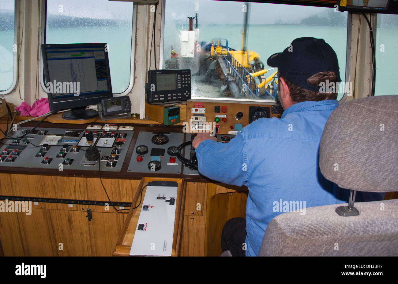 Der Skipper des Baggers an den Reglern bei Baggerarbeiten Schlamm aus dem Hafen unten. Stockfoto