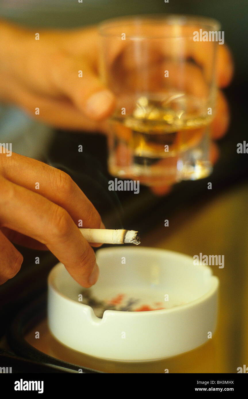 Mann, Zigarette rauchen und hält ein Glas Alkohol Stockfoto