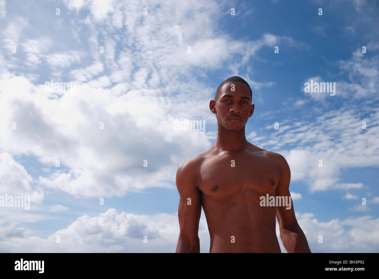 Junge nackte Oberkörper Mann gegen einen blauen Wolkenhimmel Stockfoto