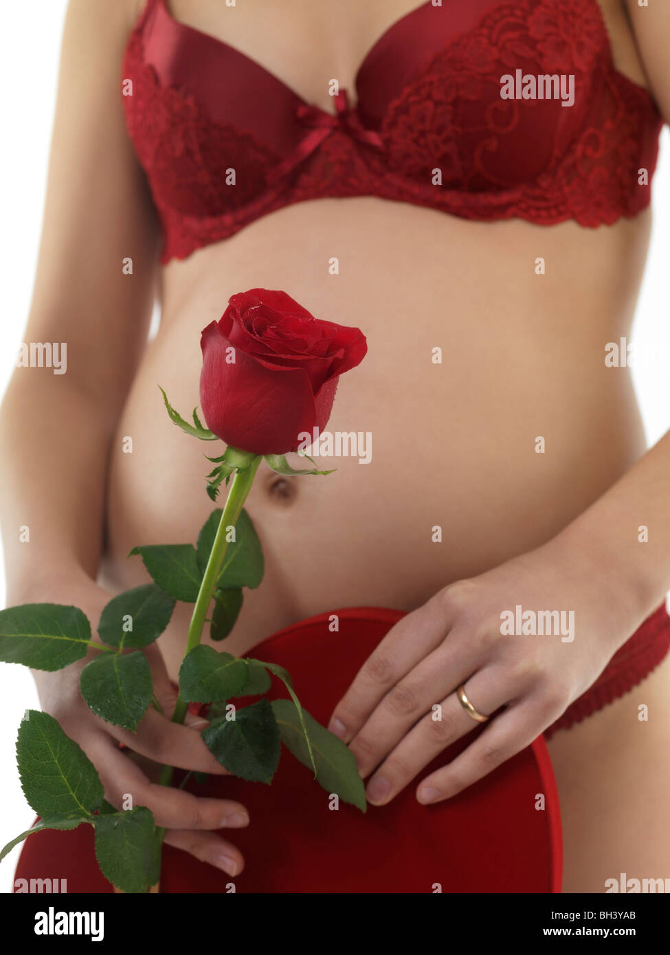 Schwangere Frau mit einer roten Rose und ein Geschenk in ihren Händen Stockfoto